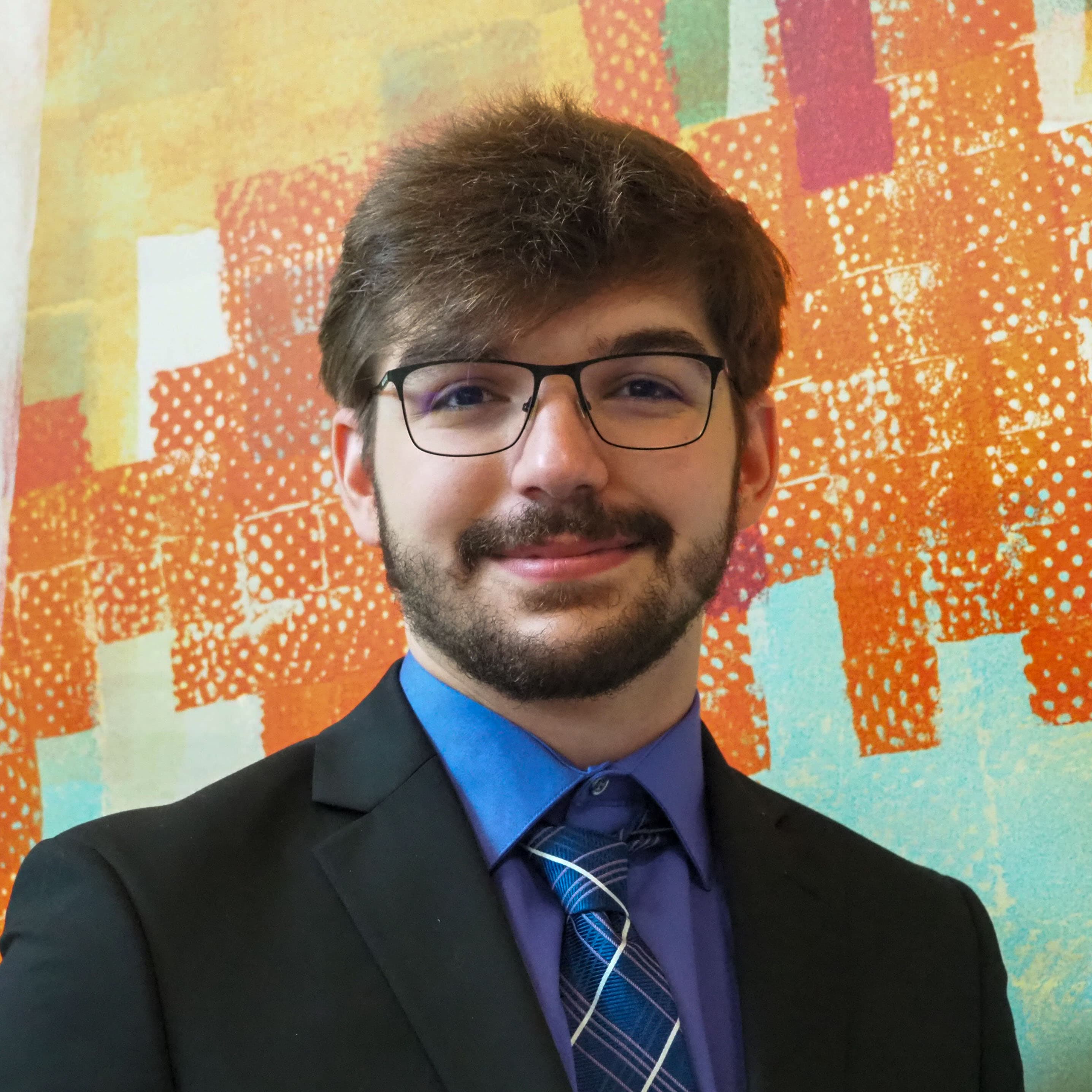 A headshot of Dylan in a suit